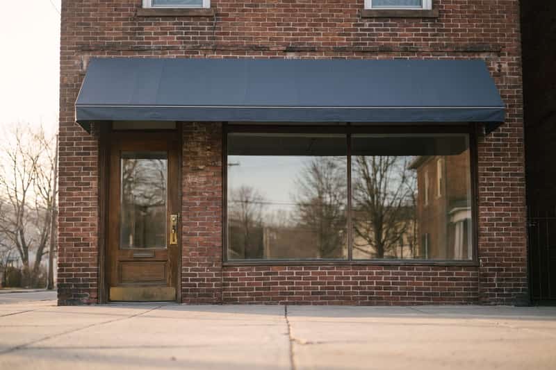 A small brick shop front with a plain awning and a large display window