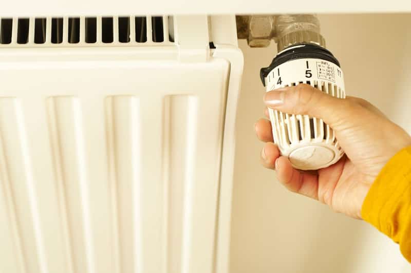 A hand turning the valve on a radiator