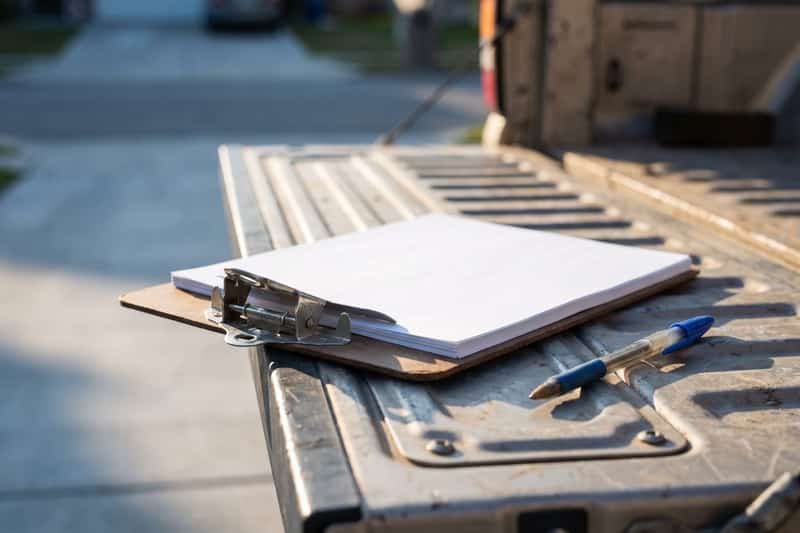A clipboard of blank paper and a pen on a pickup truck tailgate